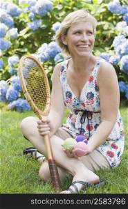 Mature woman holding tennis balls and a tennis racket