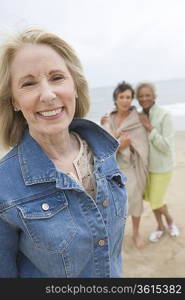 Mature woman in denim jacket on beach with her friends