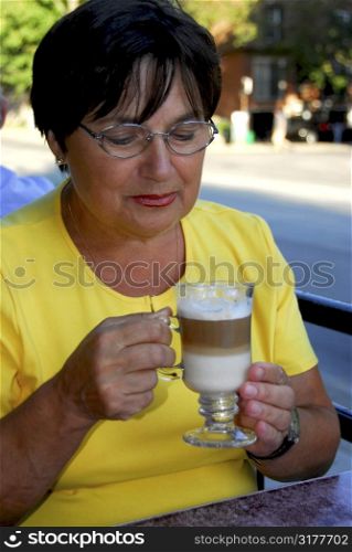 Mature woman in outdoor cafe holding a coffee