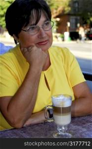 Mature woman in outdoor cafe with coffee