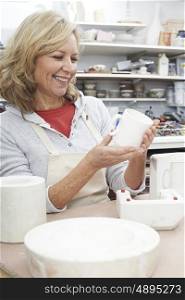 Mature Woman In Pottery Studio Casting Mug