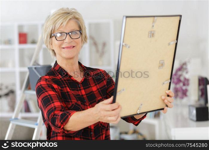 mature woman in the home holding a picture frame
