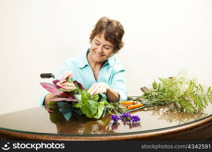 Mature woman in wheelchair, arranging a bouquet of flowers.