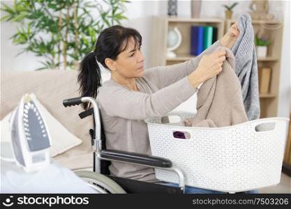 mature woman in wheelchair during ironing at home