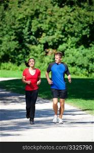 Mature woman is jogging in her free time with her young personal trainer on a sunny and warm day