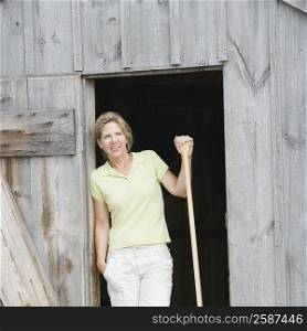 Mature woman leaning against a door and holding an oar
