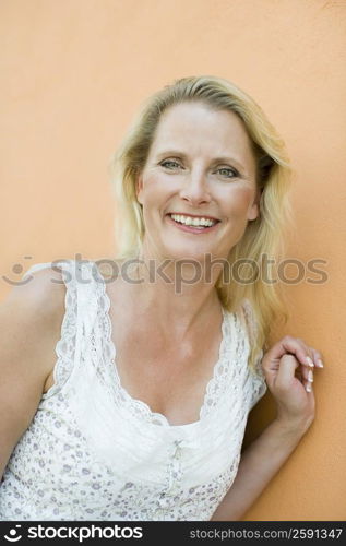 Mature woman leaning against a wall and smiling