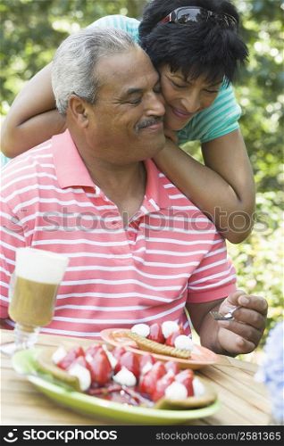 Mature woman leaning on a senior man at the breakfast table