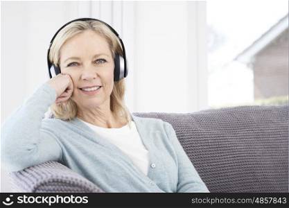 Mature Woman Listening To Music On Wireless Headphones