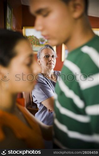 Mature woman looking at her granddaughter embracing a young man