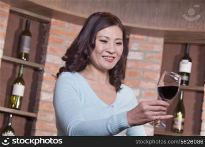 Mature Woman Looking at Wineglass, Winetasting