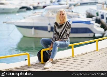 Mature woman looking serenely at the camera, sitting in a seaport.. Eldery woman looking serenely at the camera, sitting in a seaport.