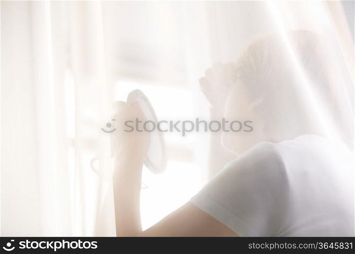 Mature woman looks at reflection in hand mirror