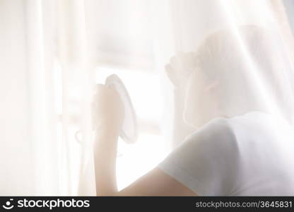 Mature woman looks at reflection in hand mirror