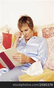 Mature woman lying in bed and reading a book