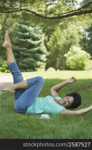 Mature woman lying on grass and exercising