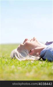 Mature woman lying on grass smiling