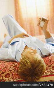 Mature woman lying on the bed listening to an MP3 player