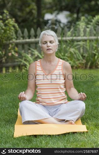 Mature woman meditating in a park