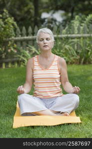 Mature woman meditating in a park