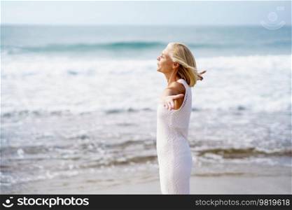 Mature woman opening her arms on a tropical beach, spending her leisure time. Elderly female enjoying her retirement at a seaside retreat.. Mature woman opening her arms on the beach, spending her leisure time, enjoying her free time