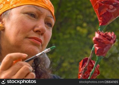 Mature woman painting flower, close-up