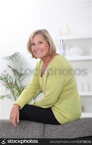 Mature woman perched on a sofa