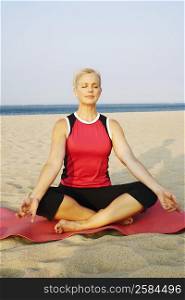 Mature woman performing yoga on the beach