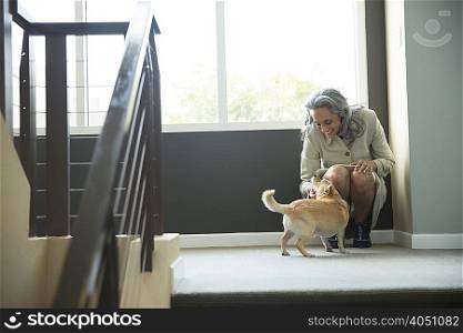 Mature woman petting her dog on stairwell