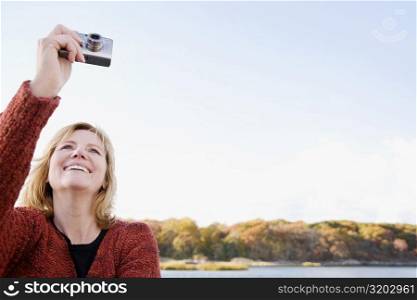 Mature woman photographing with a digital camera and smiling