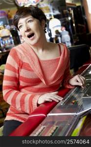 Mature woman playing on a slot machine and looking surprised