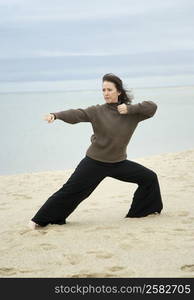 Mature woman practicing martial arts on the beach