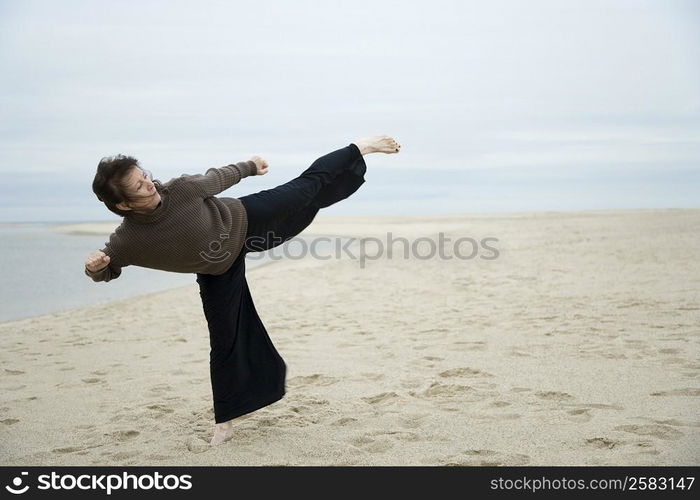 Mature woman practicing martial arts on the beach