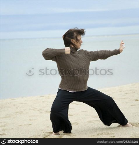 Mature woman practicing martial arts on the beach