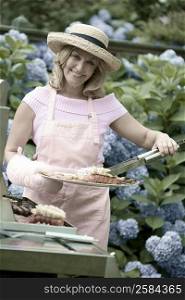 Mature woman preparing food on a barbecue grill and smiling