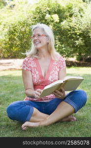 Mature woman reading a book in a park and smiling