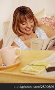 Mature woman reading a newspaper and smiling