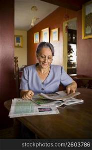 Mature woman reading a newspaper and smiling