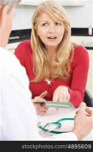 Mature Woman Reading Leaflet In Doctor's Surgery