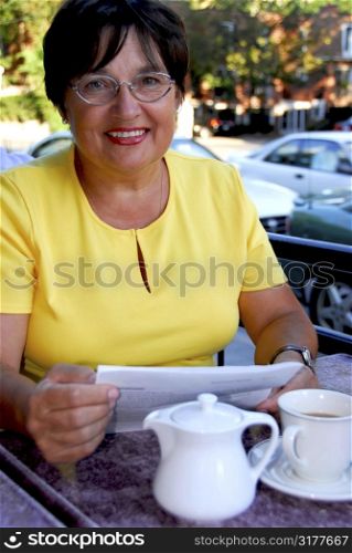 Mature woman reading papers in outdoor cafe