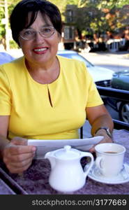 Mature woman reading papers in outdoor cafe