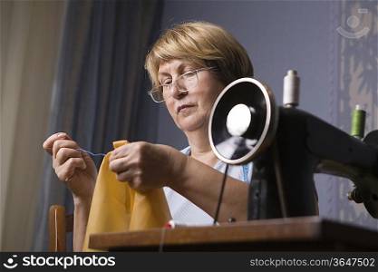 Mature woman repairing clothes