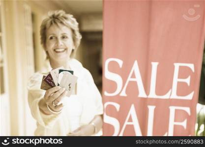 Mature woman showing credit cards and smiling