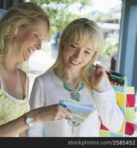 Mature woman showing photograph to a mid adult woman and smiling