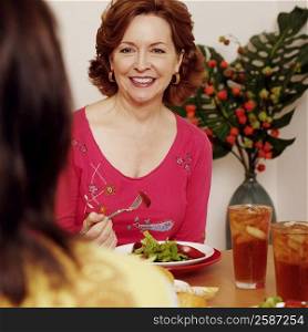 Mature woman sitting at a dining table with her friend and smiling