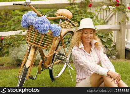 Mature woman sitting beside a bicycle