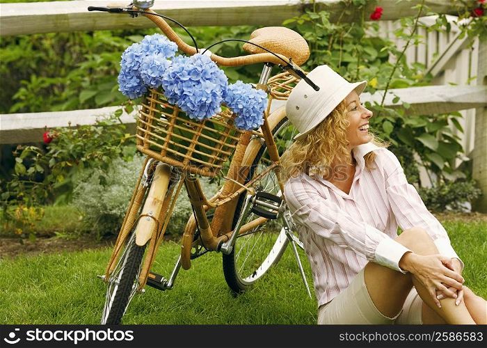 Mature woman sitting beside a bicycle
