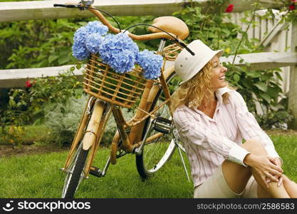 Mature woman sitting beside a bicycle