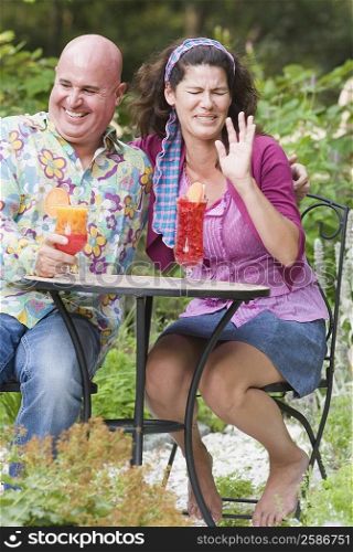 Mature woman sitting beside a mature man and making a face
