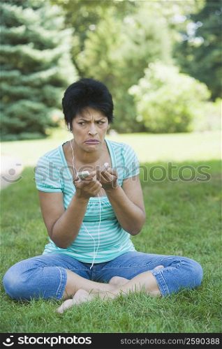 Mature woman sitting in a park and listening to an MP3 player